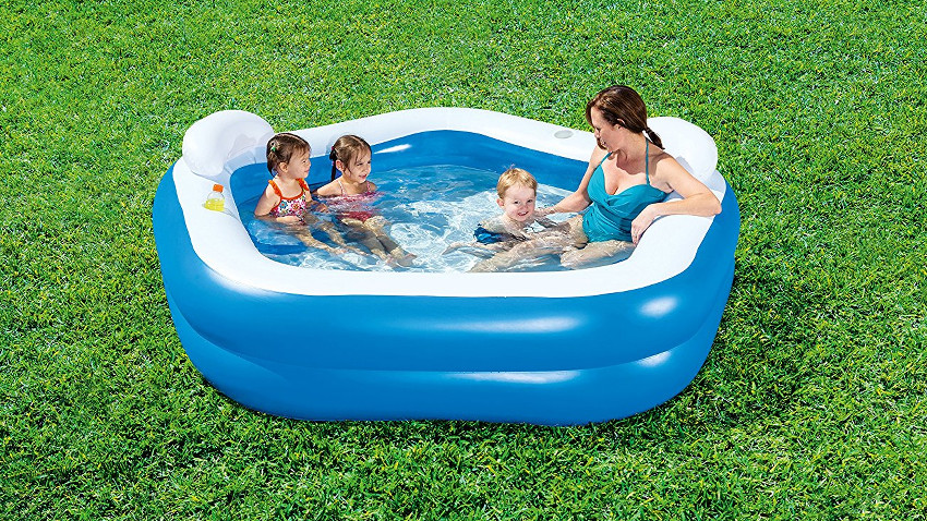 kleiner Pool auf grünem Rasen. Darin sitzen eine Frau und drei Kinder
